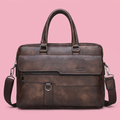 Brown Jeep briefcase with twin handles and shoulder strap on soft pink