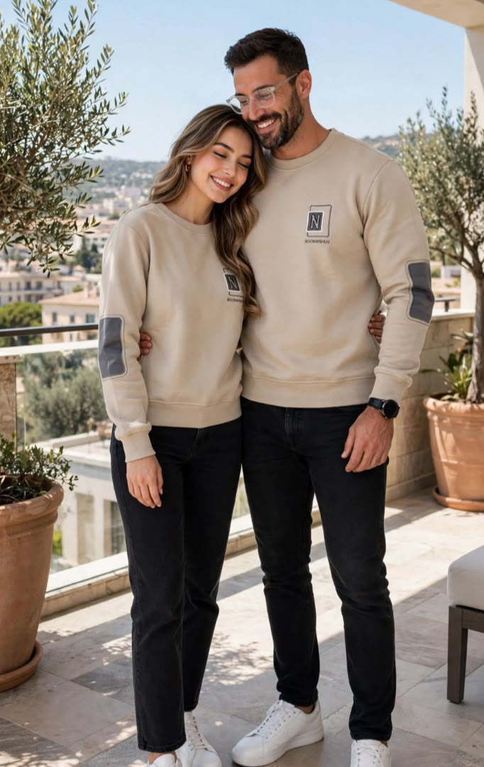 Couple wearing matching beige sweatshirts with dark elbow patches