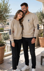 Couple wearing matching beige sweatshirts with dark elbow patches