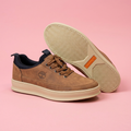 Tan lace-up sneakers with cream soles on soft pink background
