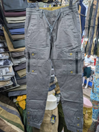 Men's grey cargo pants with zippered pockets and brass snap buttons
