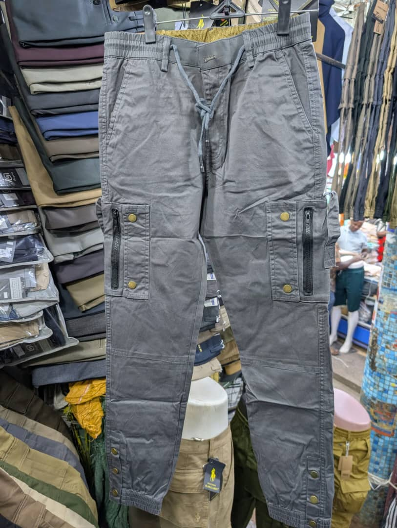 Men's grey cargo pants with zippered pockets and brass snap buttons