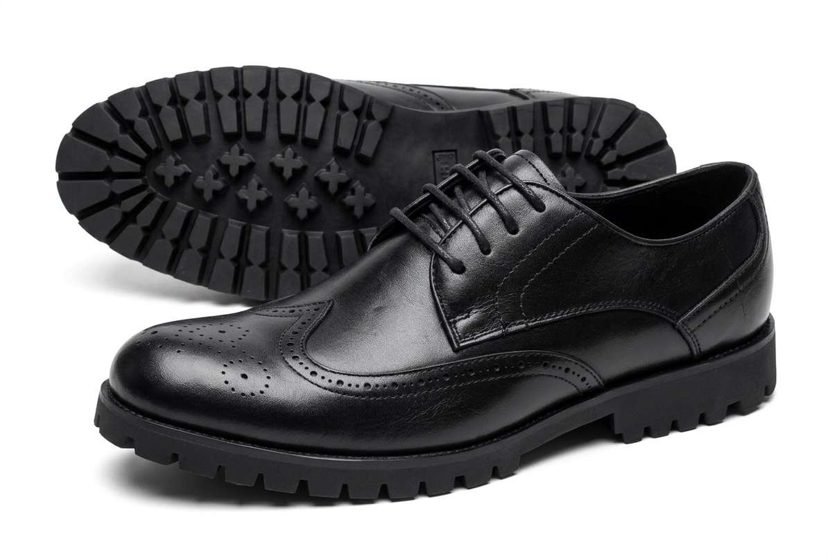 Black wingtip brogue shoes with lug soles on white background
