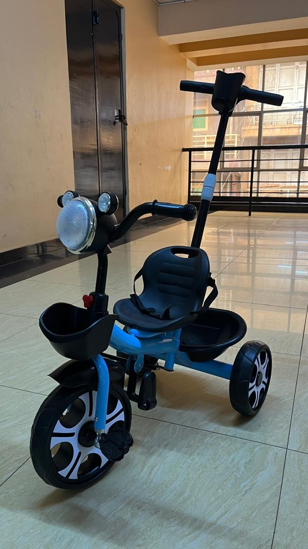 Blue kids tricycle with push handle, safety seat, front light and baskets