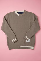 Taupe textured knit sweater with white stripe trim on a soft pink background