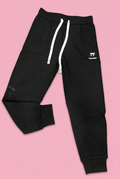 Black drawstring joggers with white 77 emblem on soft pink background