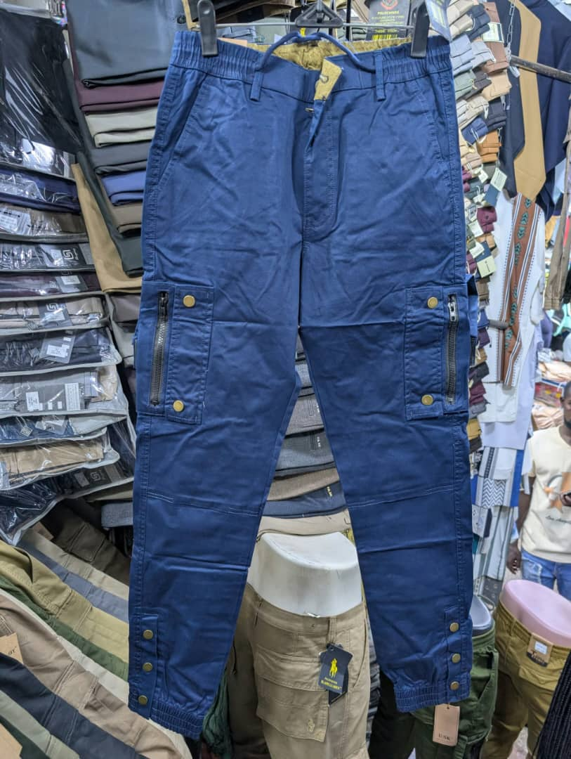 Men's navy blue cargo pants with zippered pockets and brass snap buttons
