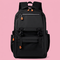 Black multi-pocket backpack with orange zipper pulls on soft pink background