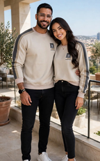 Couple wearing matching beige sweatshirts with grey sleeve stripes