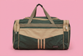 Dark green and beige travel duffel bag on soft pink background