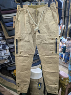 Men's khaki cargo pants with zippered pockets and white drawstring