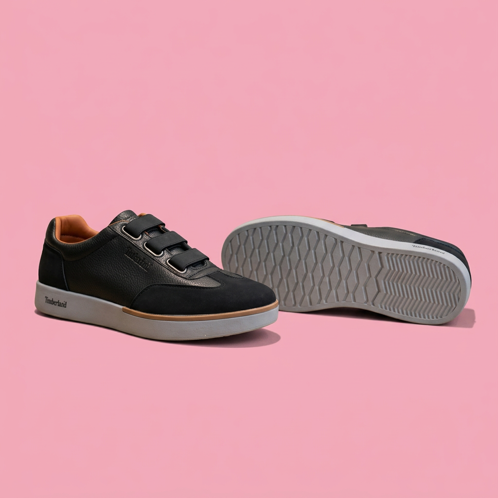 Black triple-strap sneakers with grey soles on soft pink background