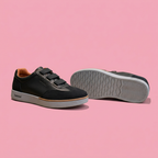 Black triple-strap sneakers with grey soles on soft pink background