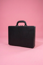 Single black briefcase on a pink background